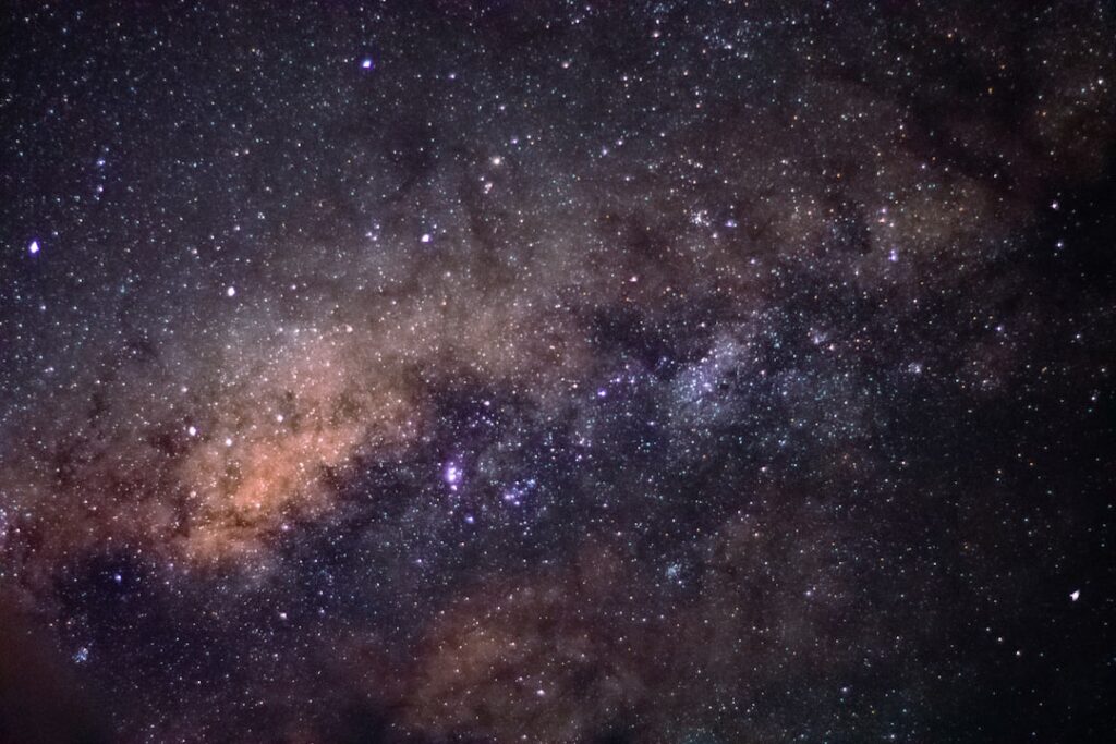 Night sky filled with stars and the Milky Way's dusty band across the center of the image.